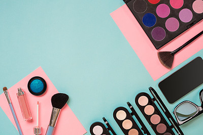 Colorful cosmetics on blue workplace with copy space. Cosmetics make up artist objects: lipstick, eye shadows, powder, tools for make-up.Top view