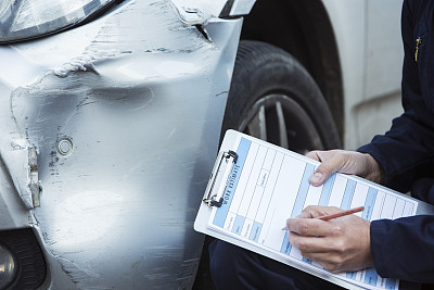 Auto Workshop Mechanic Inspecting Damage To Car