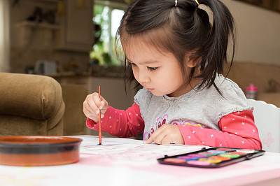 Little Asian girl learning to paint at home