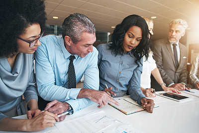 Multiracial workers discussing papers sitting in office