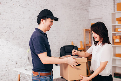 Asian businesswoman receiving parcel from courier
