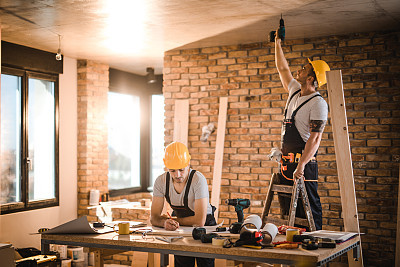 Construction workers working on home renovation process inside of an apartment.