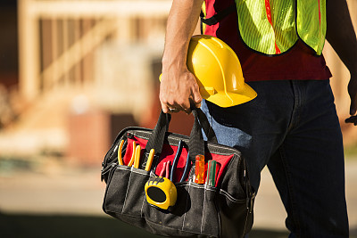 Construction worker working at a job site. Toolbag, hardhat.