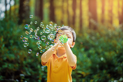 Cute little boy outdoors blowing bubbles