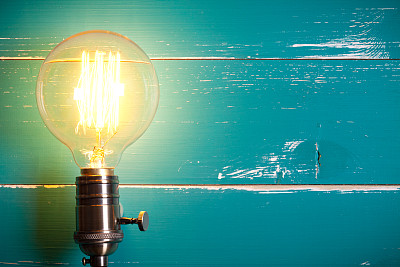 Vintage incandescent Edison type bulb on turquoise wooden table预览效果
