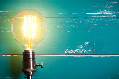 Vintage incandescent Edison type bulb on turquoise wooden table