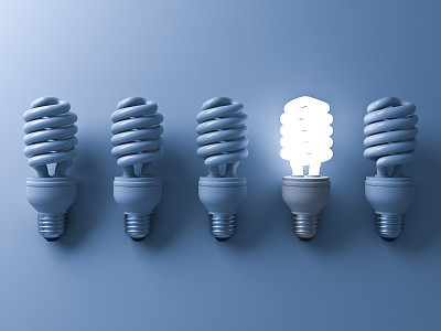 Energy saving light bulb , one glowing compact fluorescent lightbulb standing out from unlit light bulbs on blue background , individuality and different creative idea concepts . 3D rendering