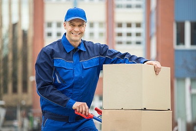 Deliveryman With Trolley Loaded With Cardboard Boxes