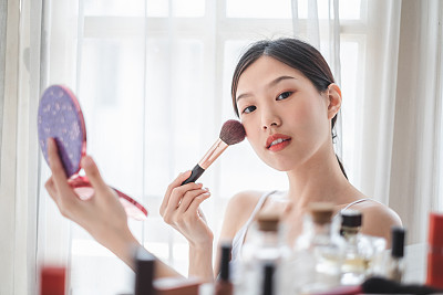 Young beautiful Asian woman applying cosmetics make up on her face, health beauty skin care and make up concept