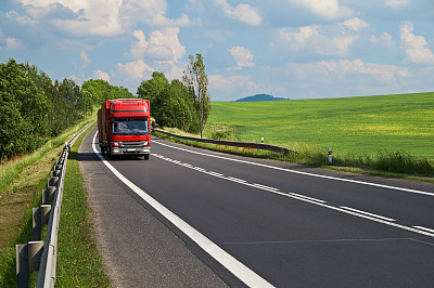 Small truck traveling on the asphalt road in a landscape