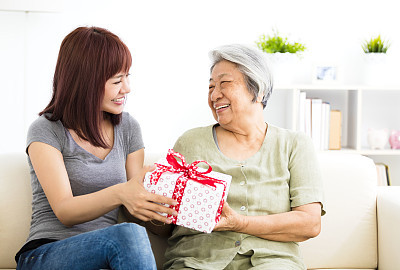 happy  young woman giving  present to grandmother