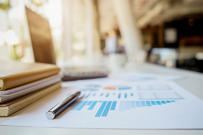 Business concept with copy space. Office desk table with pen focus and analysis chart, computer, notebook, cup of coffee on desk.Vintage tone Retro filter.