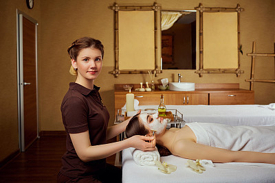 Cosmetologist makes a face mask for a woman in  spa salon