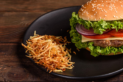 Tasty grilled homemade burger with beef, tomato, cheese, cucumber and lettuce. Delicious grilled burgers
