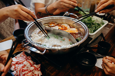 Korean hot pot meal. Hands taking food with chopsticks.