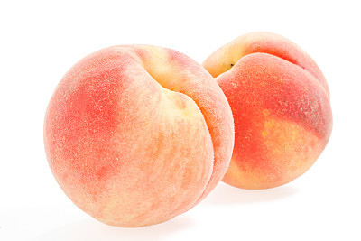 Two whole peaches on a white background