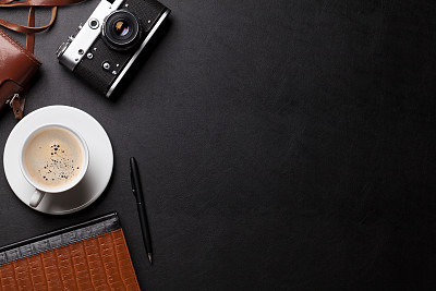 Office desk with camera, coffee and notepad