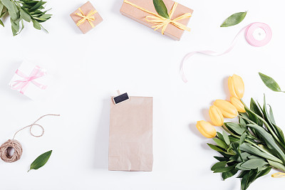 Gifts, tulips, ribbon, rope on a white table