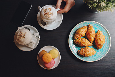 Young man relaxing in the cafe, with espresso and croissants