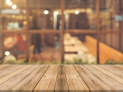 Wooden board empty table top on of blurred background. Perspective brown wood table over blur in coffee shop background - can be used mock up for montage products display or design key visual layout.