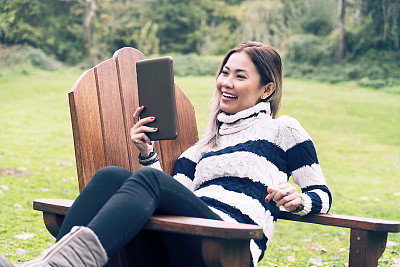 Asian woman live chatting with mobile digital tablet in woods