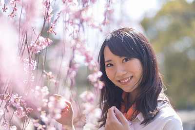 Young woman standing nearby cherry blossoms