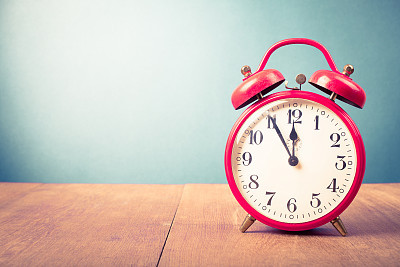 Old alarm clock with five minutes to twelve o'clock. Retro style filtered photo