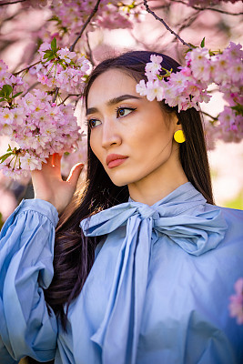 Beautiful young asian woman in blooming cherry blossoms garden