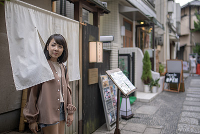 Asian tourist going through Noren entrance of Japanese traditional restaurant