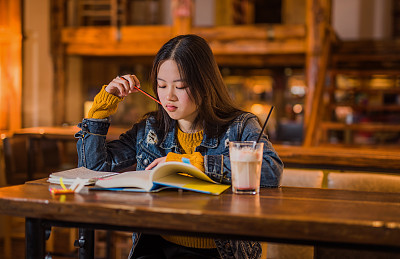 Beautiful young Asian woman studying in cafe.