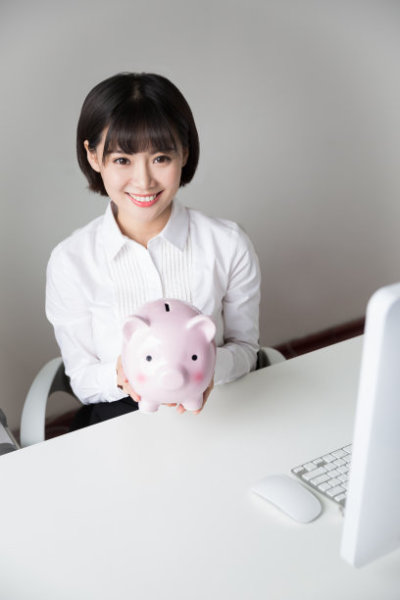 young girl sitting in the office holding model pig piggy bank