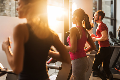 Three people exercising on treadmills in a gym.