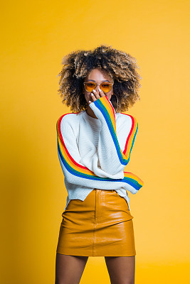 Surprised afro girl standing against yellow background