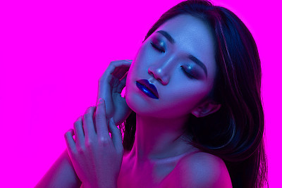 High Fashion model woman in colorful bright lights posing in studio