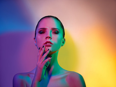 High Fashion model woman in colorful bright lights posing in studio