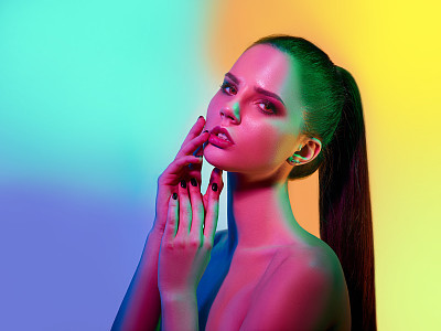 High Fashion model woman in colorful bright lights posing in studio