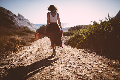 Bohemian girl in skirt and crop top walking in nature