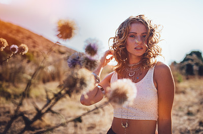 Young woman in boho style standing in field in summer