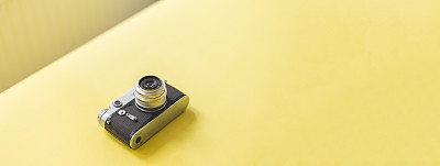 Old camera on pastel yellow background