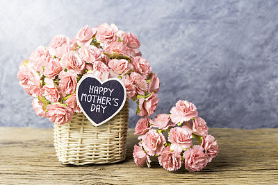 Happy mothers day concept of Paper carnation in weave basket on old wood with copy space