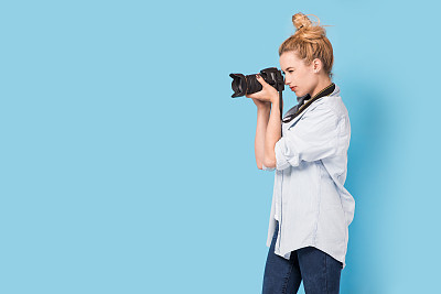 Young blonde photographer is taking a photo.