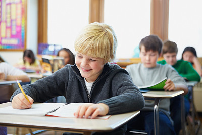 Boys and girls doing school work in classroom