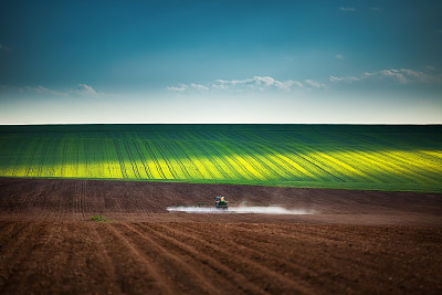Farming tractor plowing and spraying on field