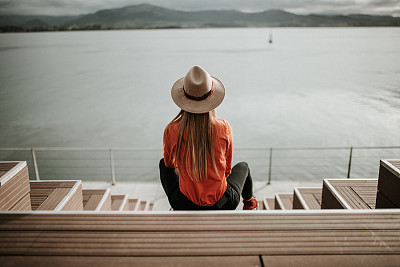 Young woman with hat contemplating a beautiful coastal landscape