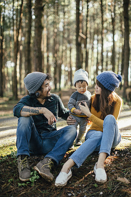 Baby Holding Pine cone with family in forest.