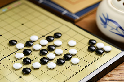 Chinese go game board, close up view of playing black and white stone pieces