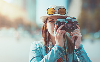 Hipster girl making picture with retro photocamera, focus on camera