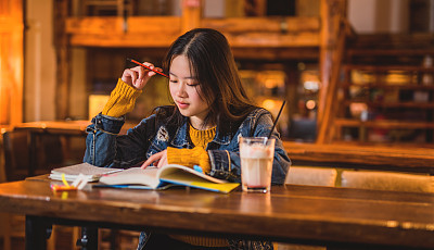 Happy young Asian woman studying in cafe.