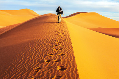 Male tourists walking on the sand dunes, morning, Mhamid, Morocco