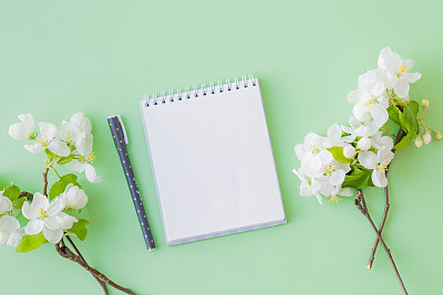 Mockup white notebook with spring white flowers on a green background